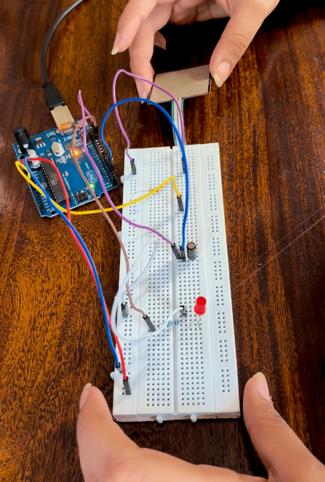 Tabletop breadboard circuit connected to an Arduino, with wiring and LED output
